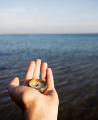 photo of hand with compass at sea